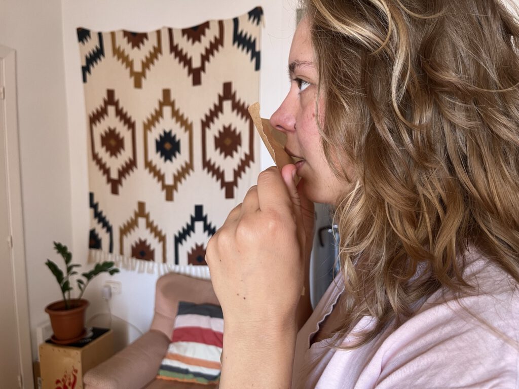 Singing with a sheet of baking paper in front of mouth.